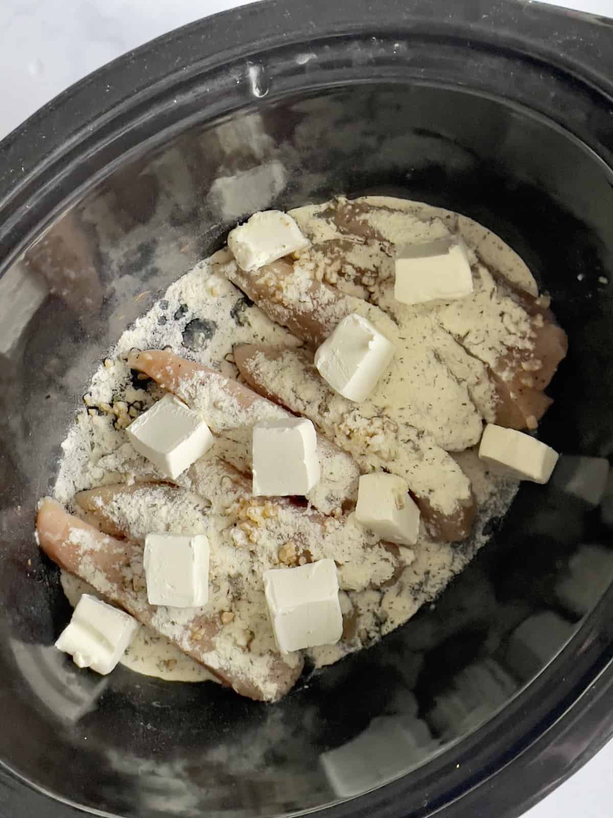 chicken breasts topped with cream cheese in a slow cooker