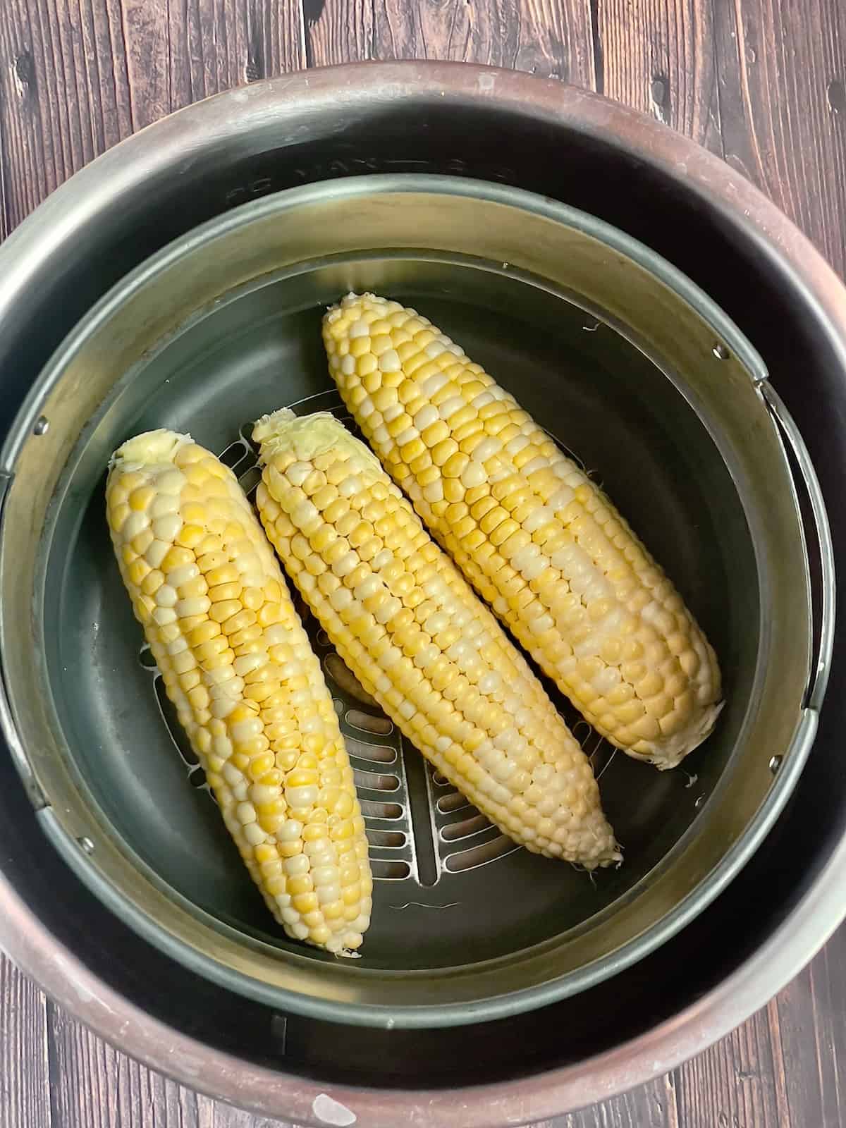 uncooked corn ears in an air fryer basket
