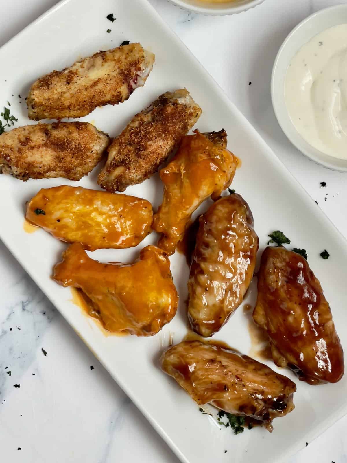 air fryer frozen chicken wings tossed with sauces on a white plate