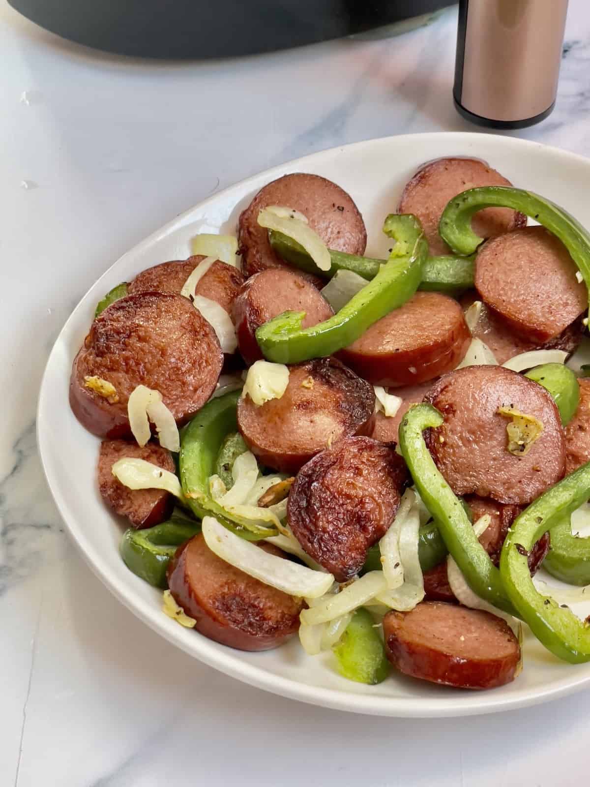 air fried kielbasa, peppers and onions on a white plate