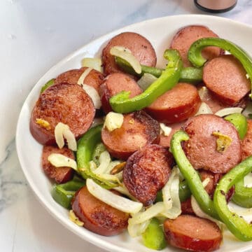 air fried kielbasa, peppers and onions on a white plate