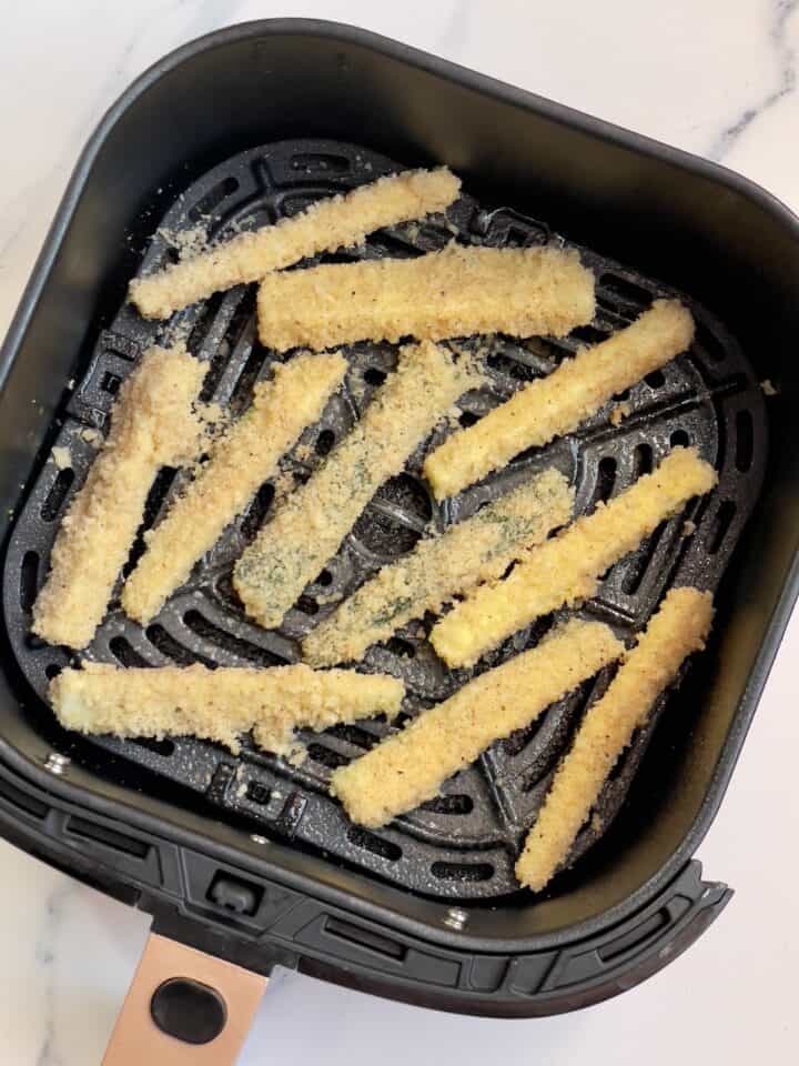breaded zucchini fries in an air fryer basket