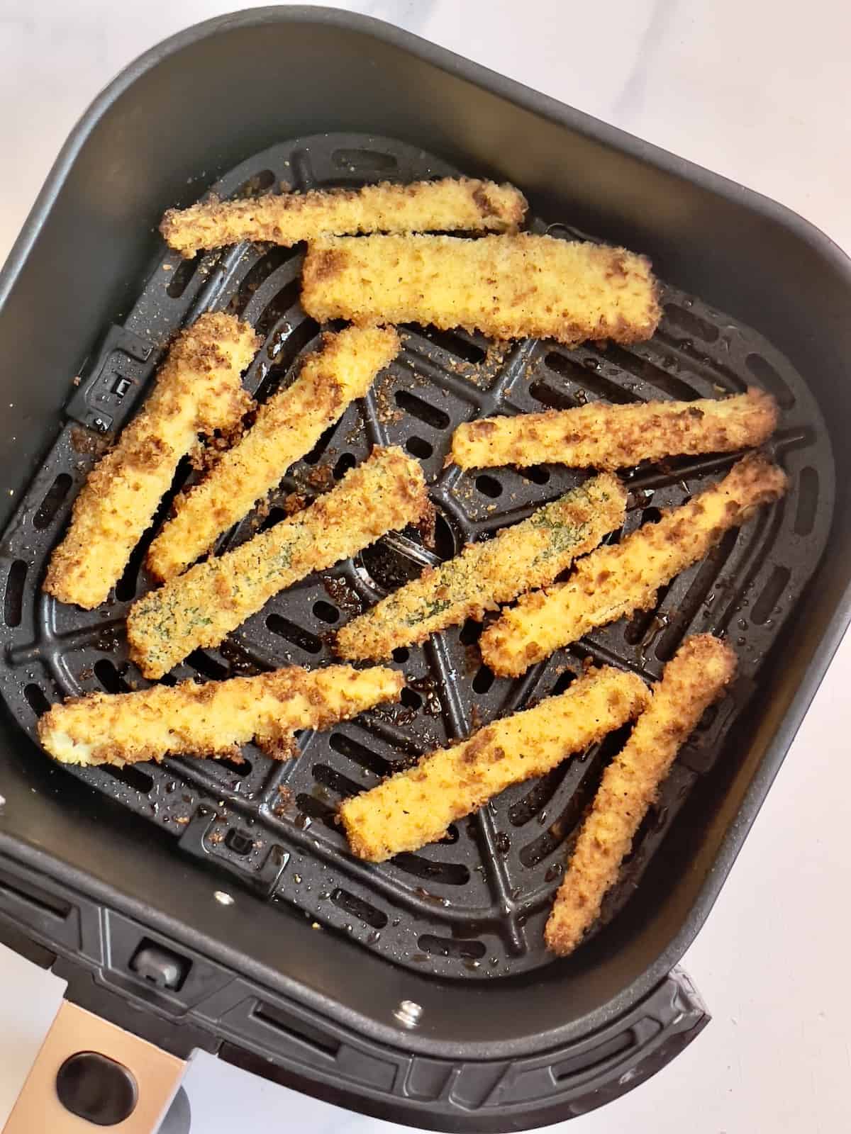 air fried zucchini fries in an air fryer basket