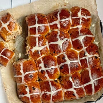 bread machine hot cross buns on a parchment paper decorated with icing crosses