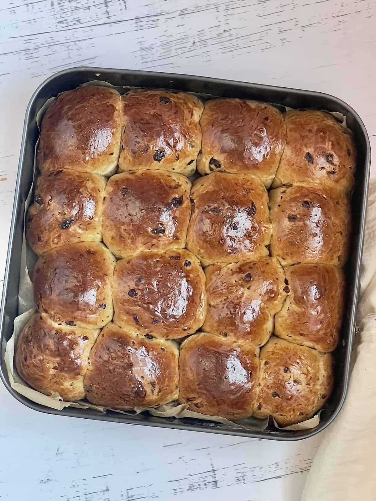 baked hot cross buns in a square pan cooling