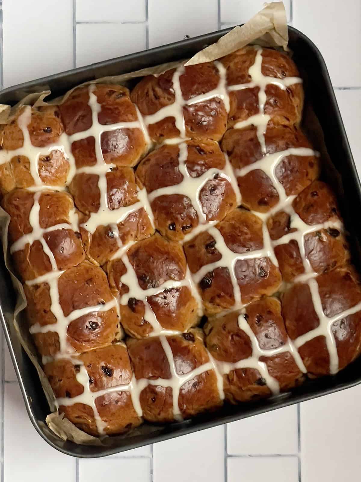 icing crosses drizzled over hot cross buns in a pan