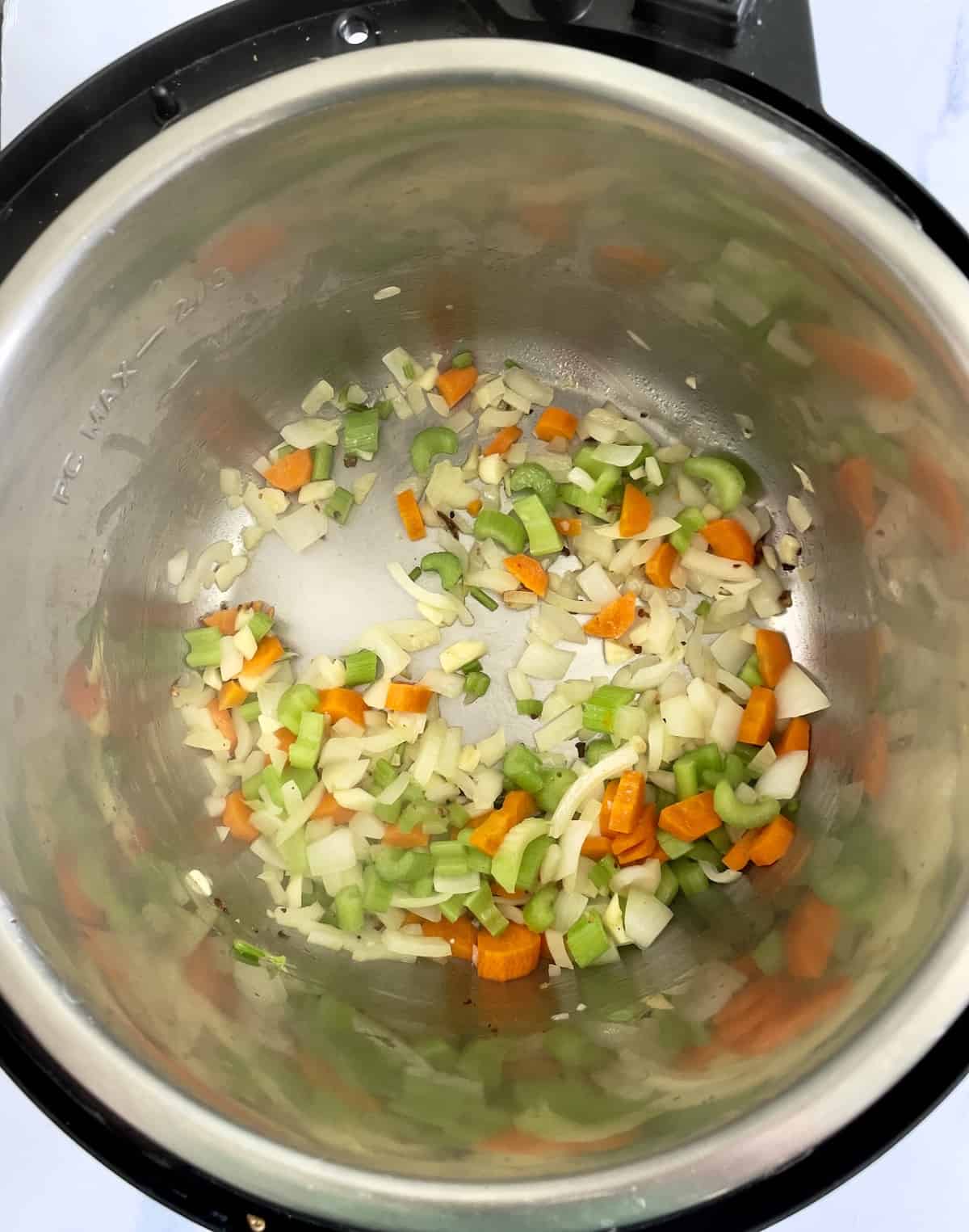 carrots, celery, onion, and garlic in the inner pot of a pressure cooker