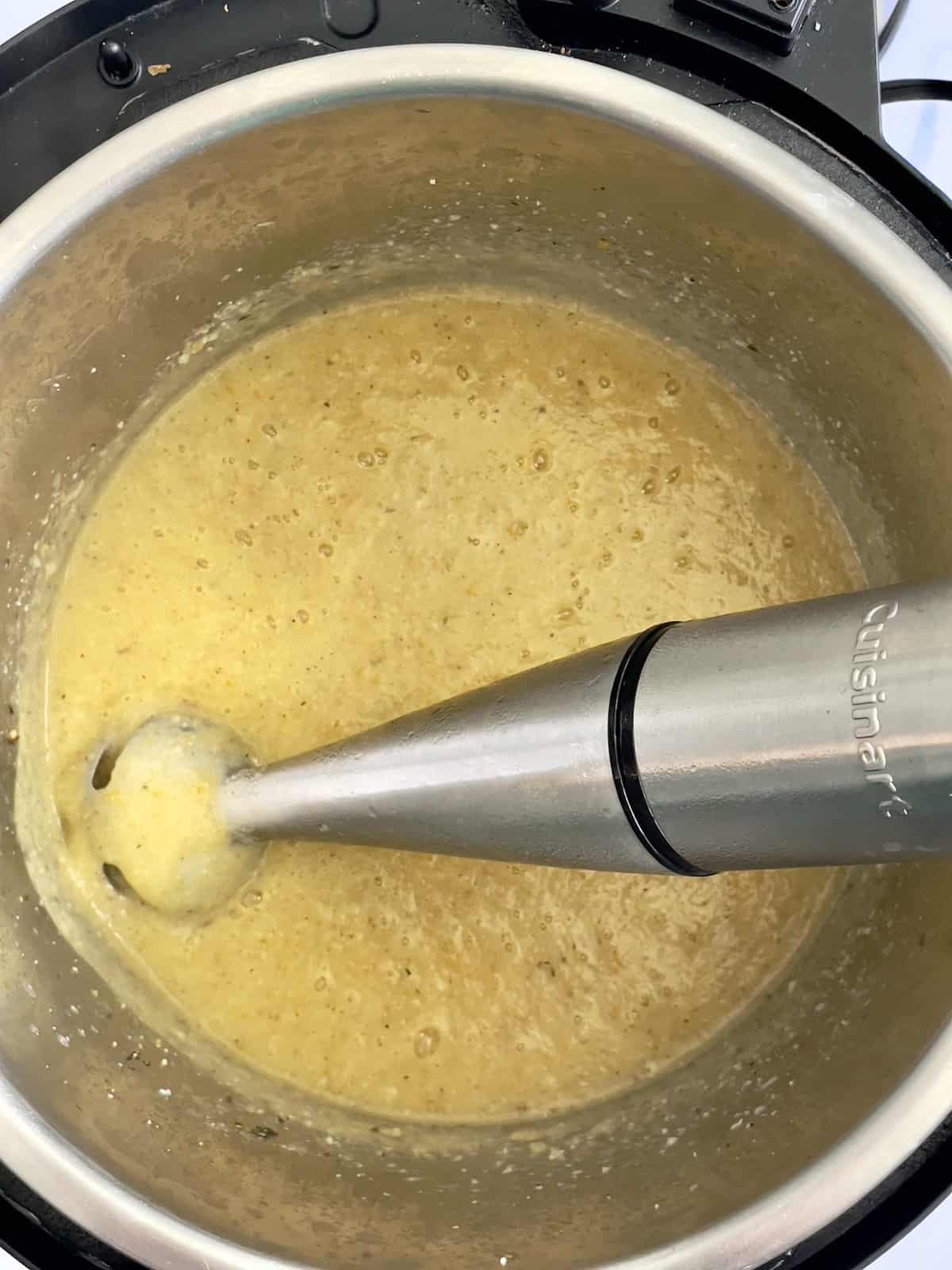 cauliflower soup being blended with an immersion blender 