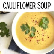 instant pot cauliflower soup in a white bowl topped with parsley and red pepper