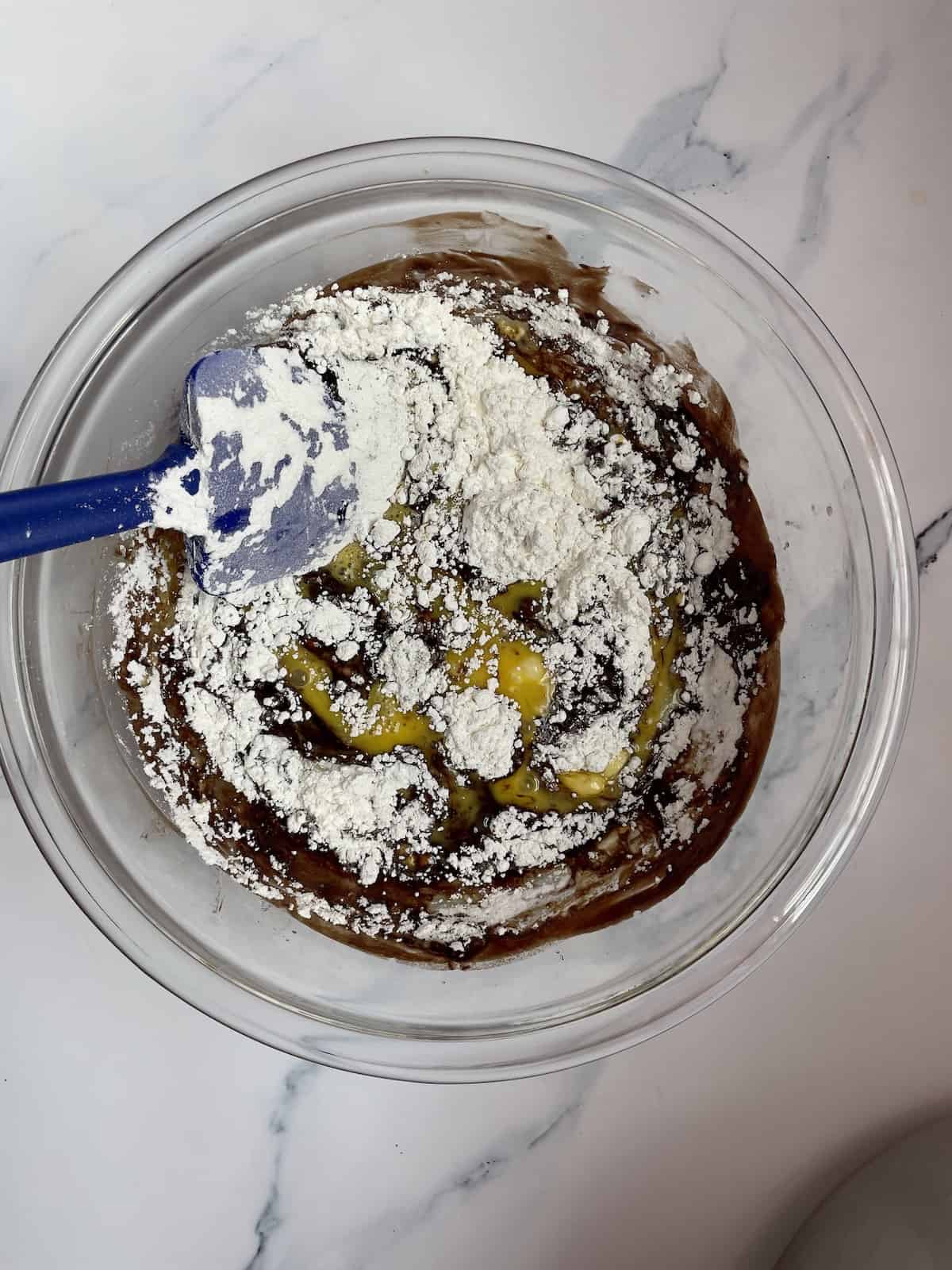 flour, chocolate, butter, and eggs in a glass bowl