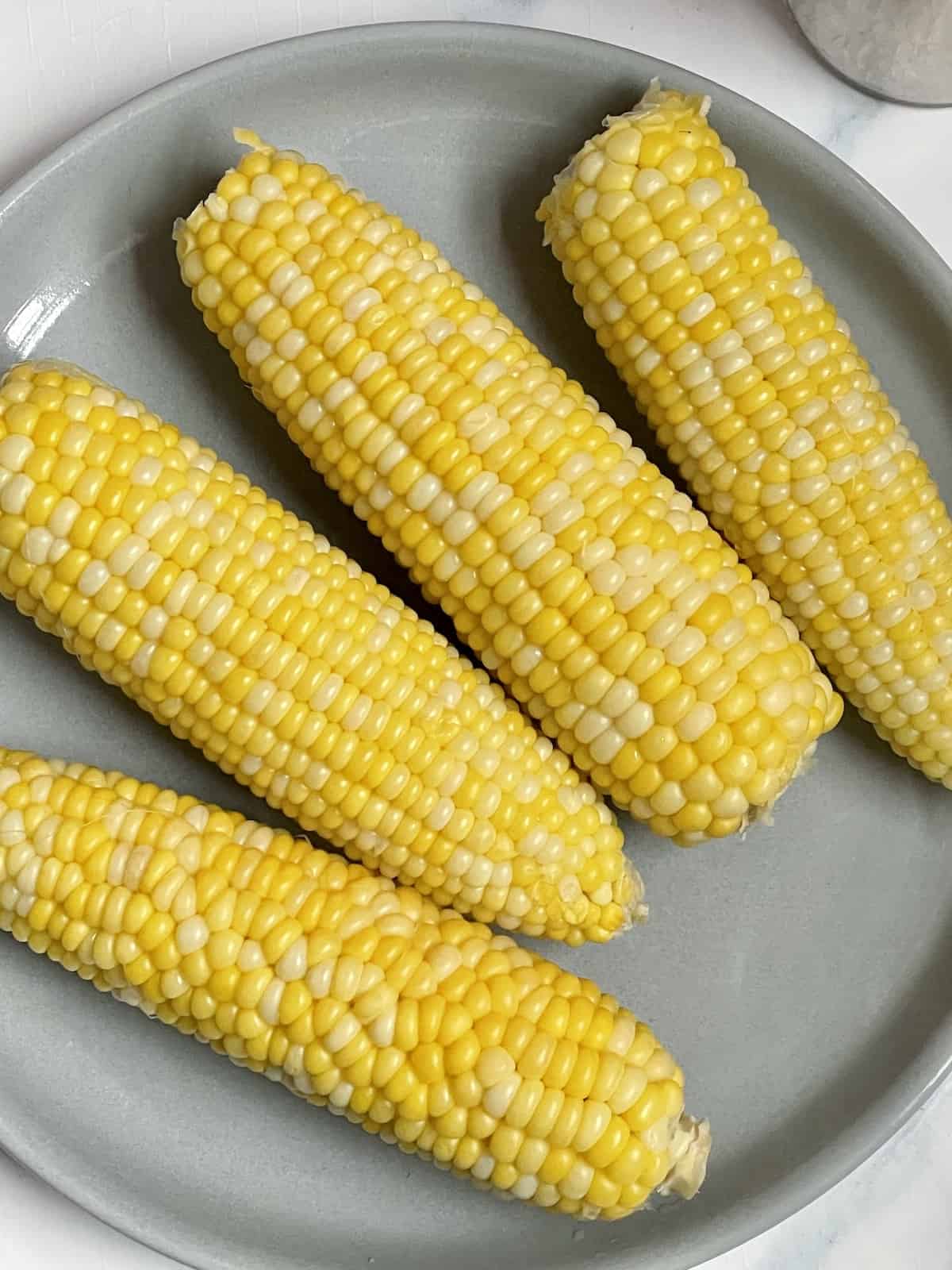 pressure cooked corn on the cob on a gray plate 