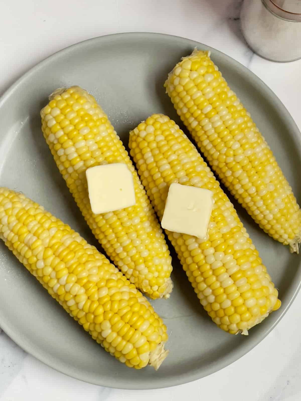 corn on the cob with butter on a gray plate