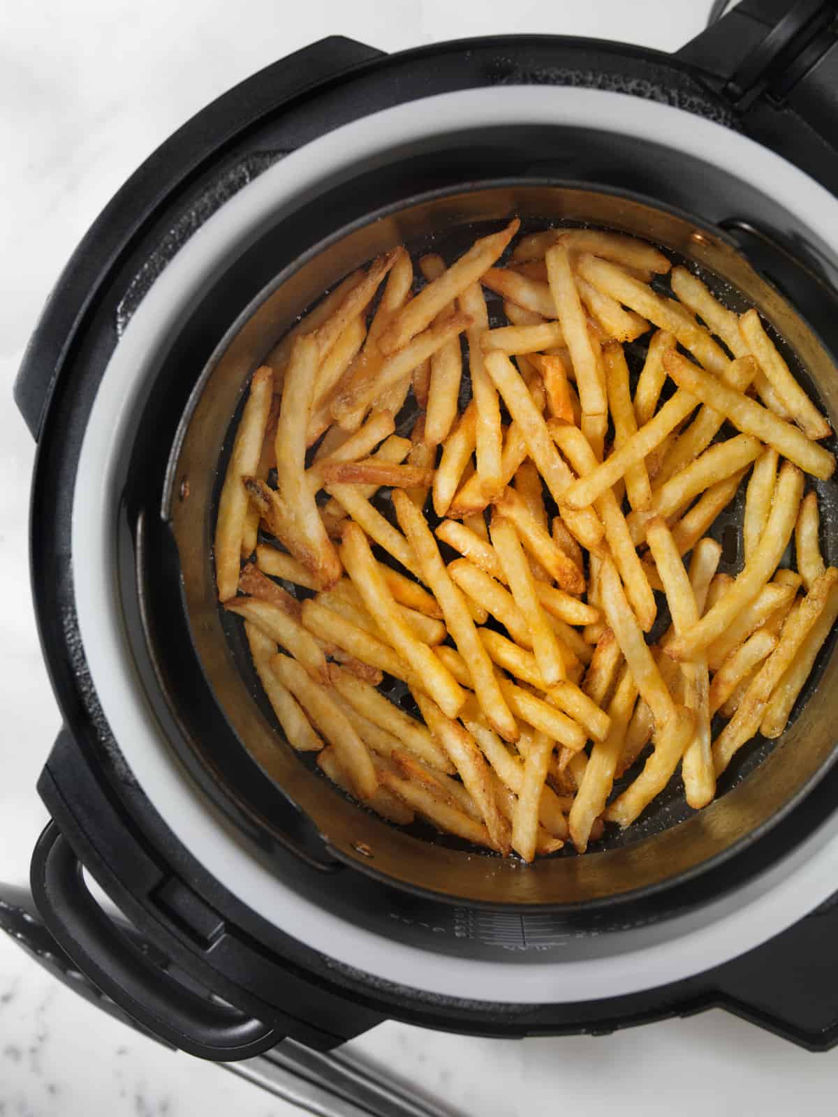 french fries stacked in an air fryer basket