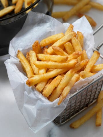 air fryer frozen french fries in a fry basket
