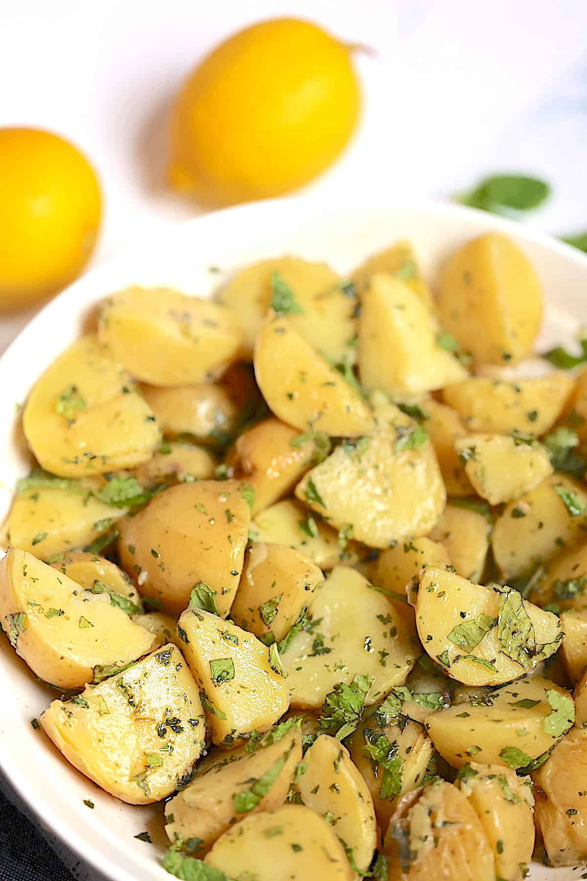 instant pot potato salad in a white bowl surrounded by lemons