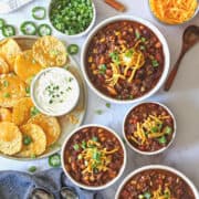 instant pot chili topped with cheese and scallions in 3 bowls
