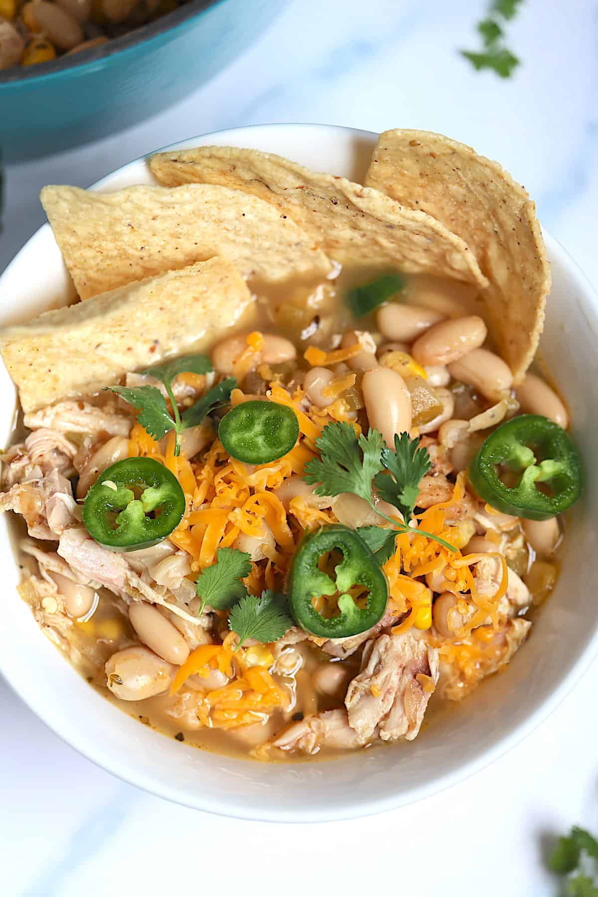 chicken chili with tortilla chips in a white bowl