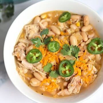 instant pot white chicken chili topped with cilantro and jalapenos in a white bowl
