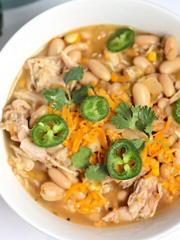 instant pot white chicken chili topped with cilantro and jalapenos in a white bowl