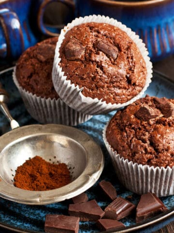 double chocolate muffins on a plate with cocoa and chocolate chips