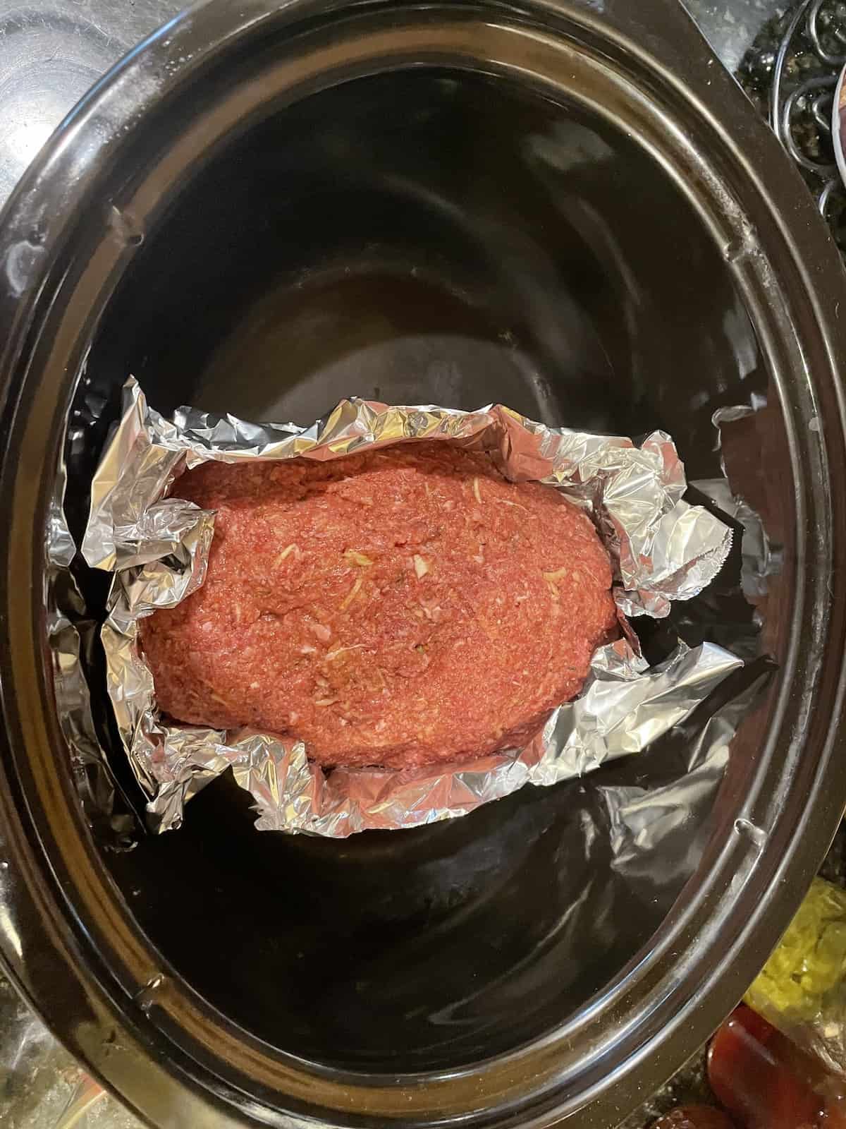 meatloaf wrapped in foil in a slow cooker