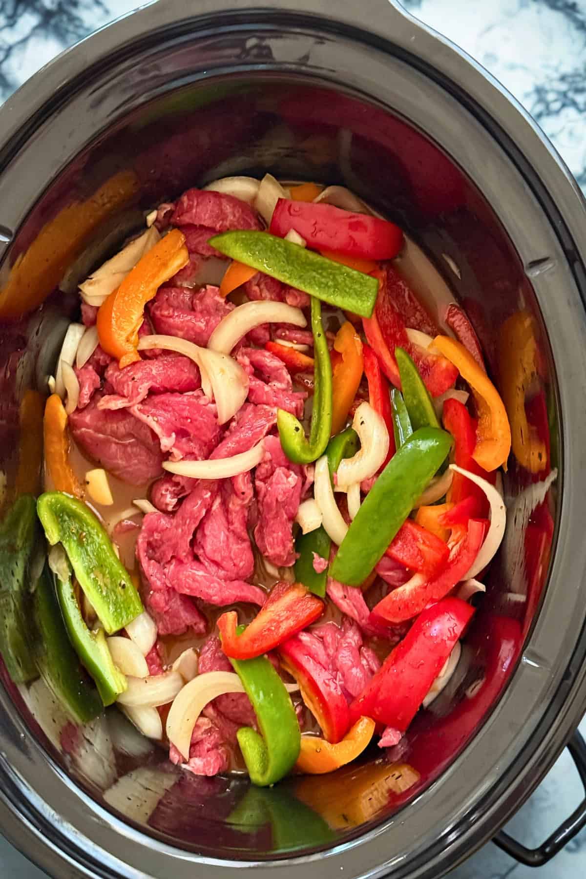 peppers, onions and beef in a crockpot