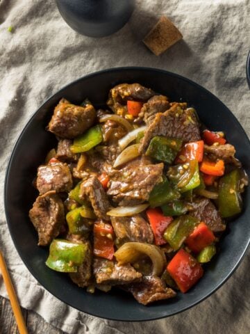 slow cooker pepper steak over rice in a black bowl