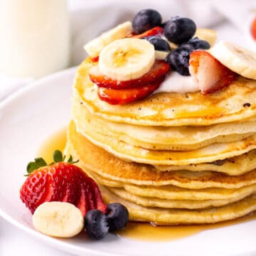 almond milk pancakes in a stack with strawberries, blueberries and banana