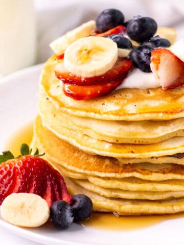almond milk pancakes in a stack with strawberries, blueberries and banana