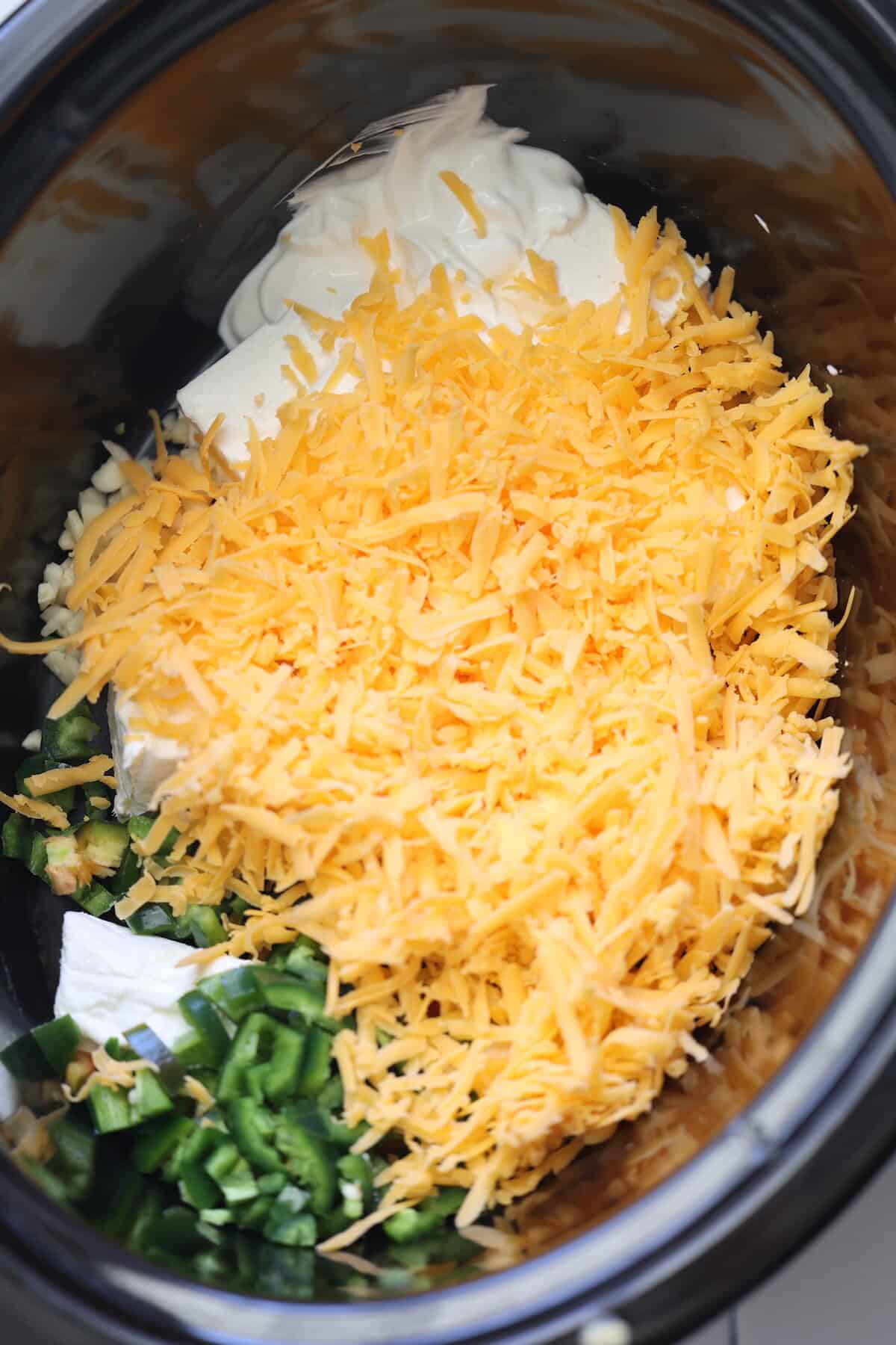 cheddar cheese, sour cream, cream cheese, jalapeno, and garlic in a crockpot