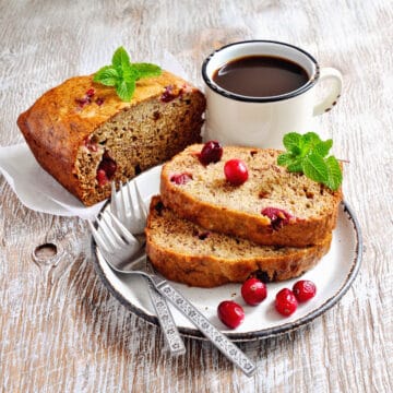 bread machine cranberry orange bread slices on a plate with fresh cranberries and mint