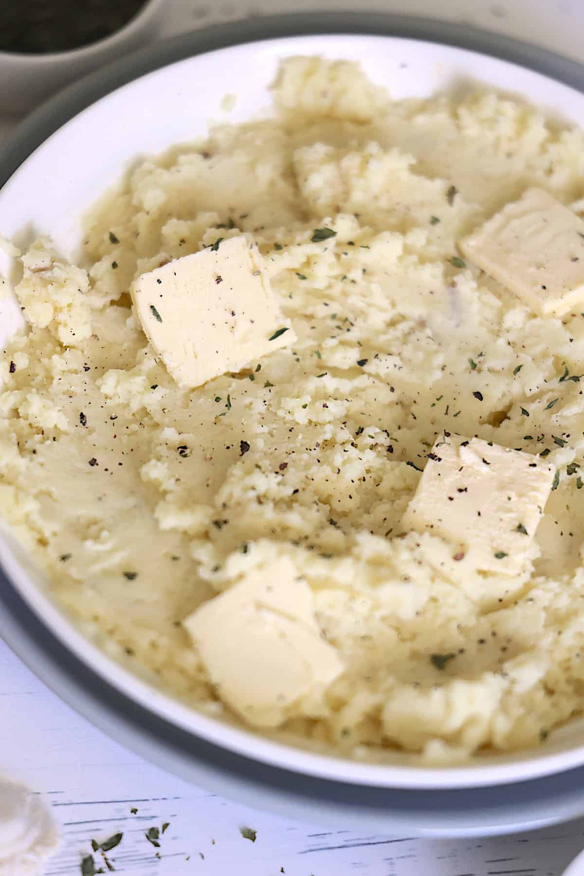 instant pot garlic mashed potatoes in a white bowl topped with butter and black pepper
