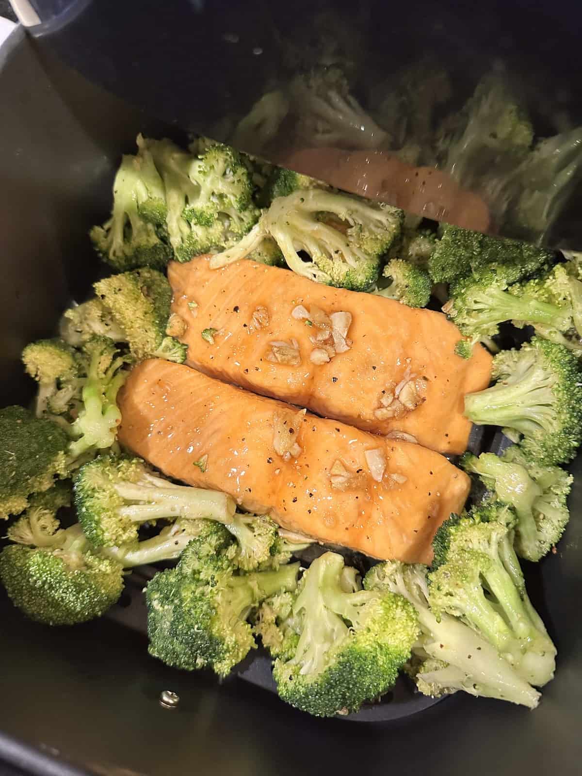 air fried maple salmon in an air fryer basket surrounded by broccoli florets