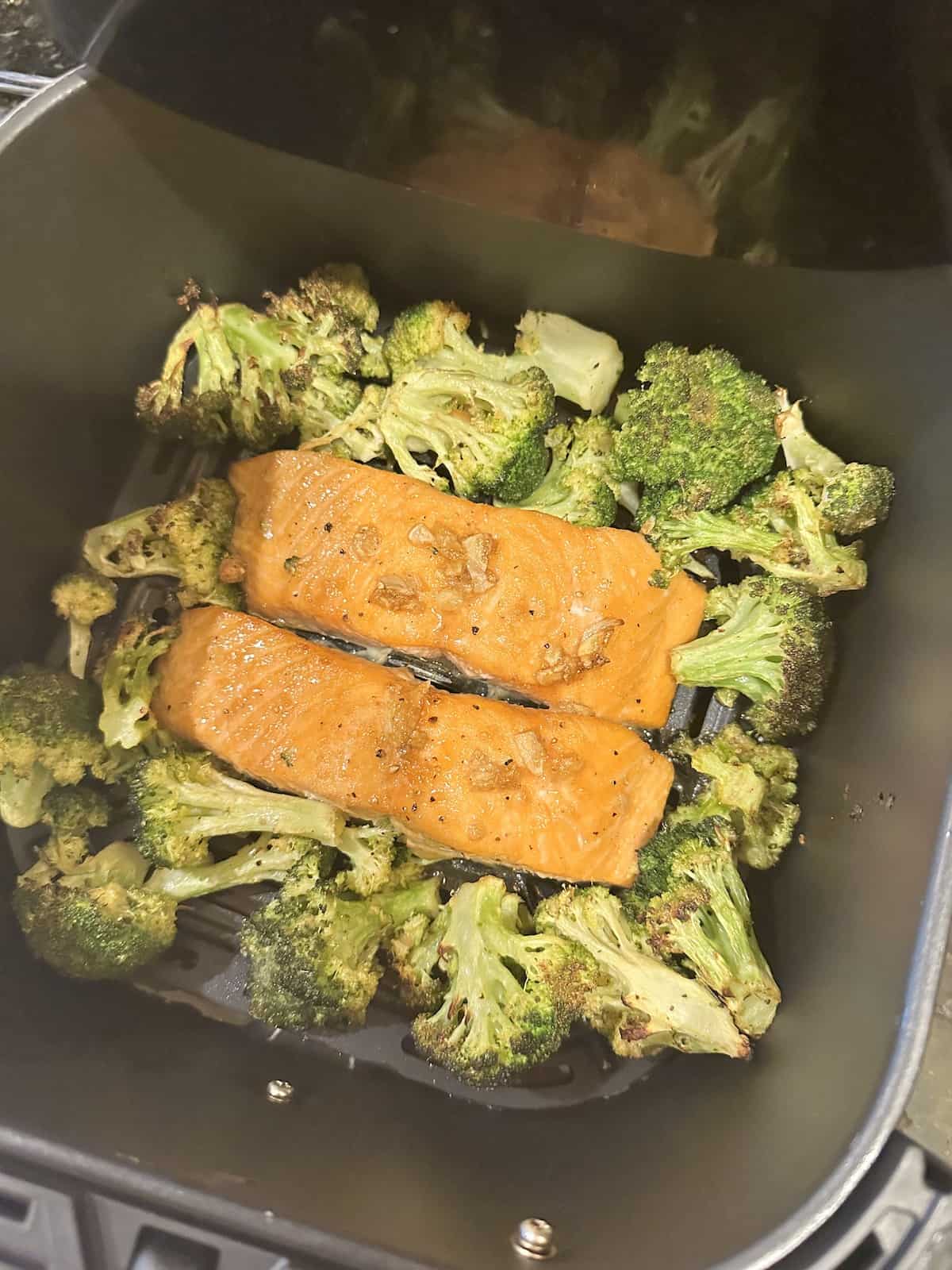 air fryer salmon and broccoli florets in an air fryer basket