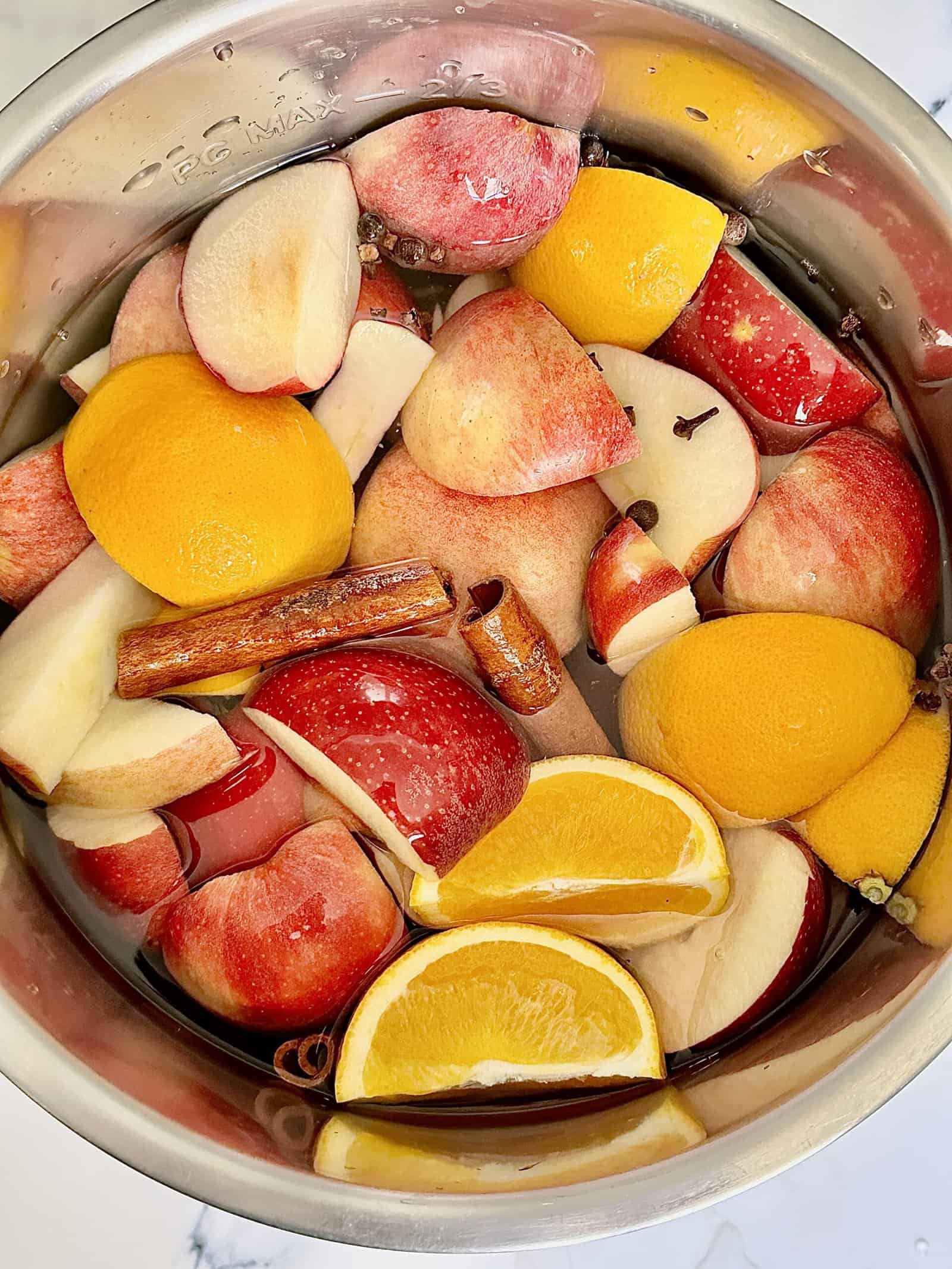 apples, oranges, whole spices and water in a pressure cooker