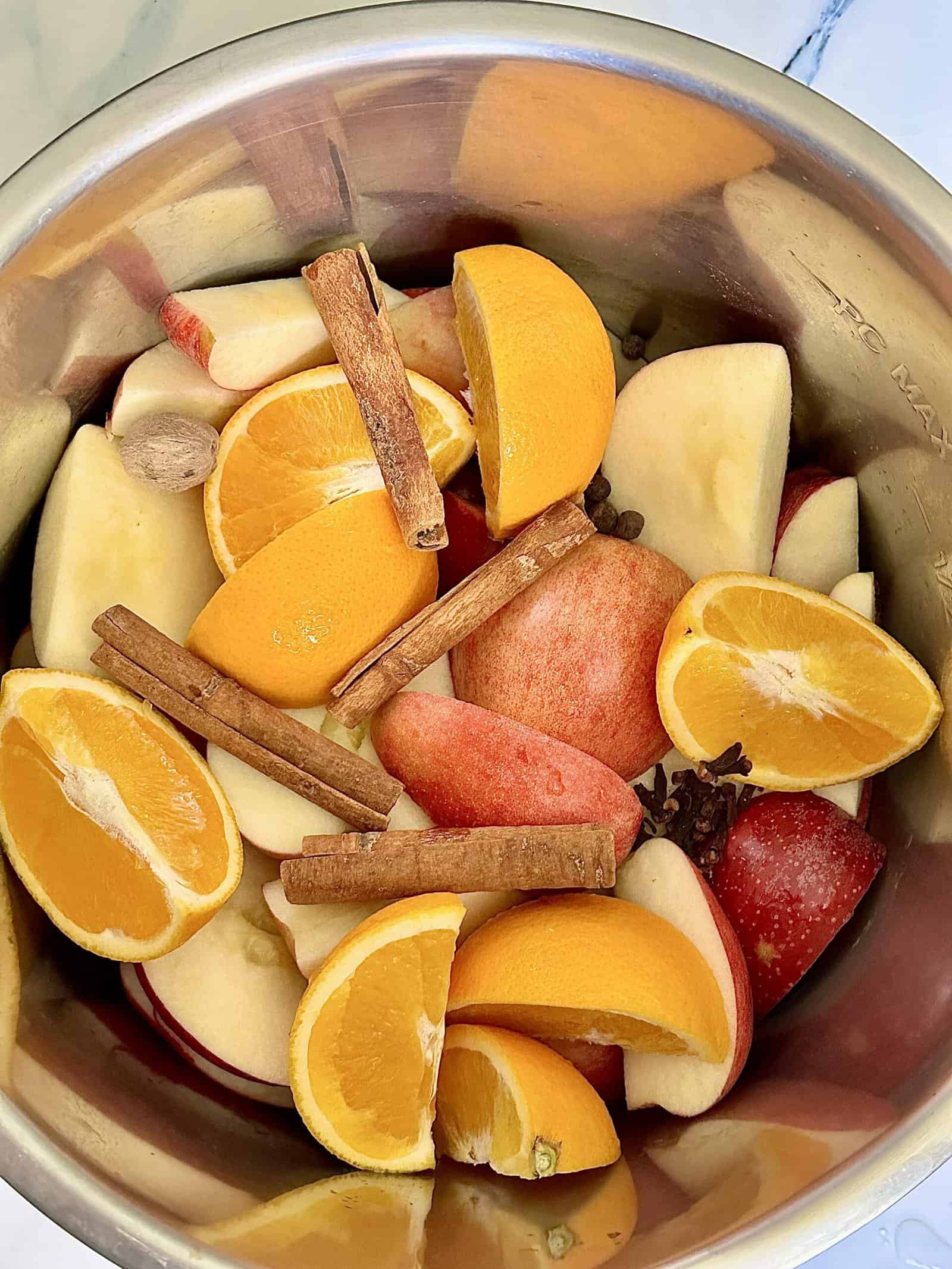 apples, oranges, whole spices and water in a pressure cooker
