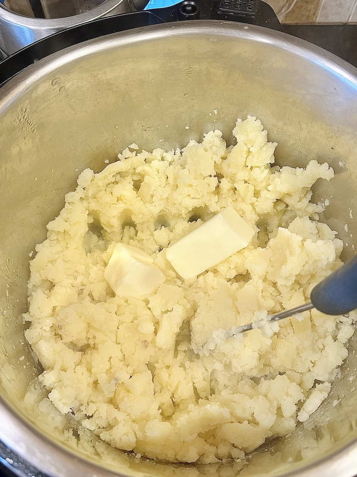 mashed potatoes in a pressure cooker with a stick of butter, milk, salt and pepper