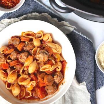 slow cooker sausage casserole in a white bowl on a blue placemat