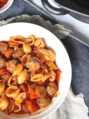 slow cooker sausage casserole in a white bowl on a blue placemat