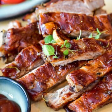 slow cooker country style ribs on a plate topped with barbecue sauce and green herbs