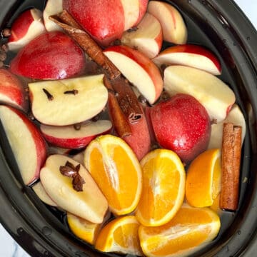 apples, oranges and whole seasonings for apple cider in a crockpot