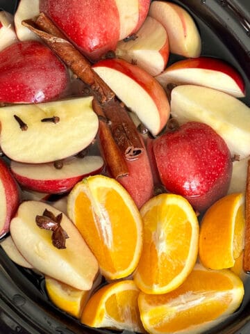 apples, oranges and whole seasonings for apple cider in a crockpot