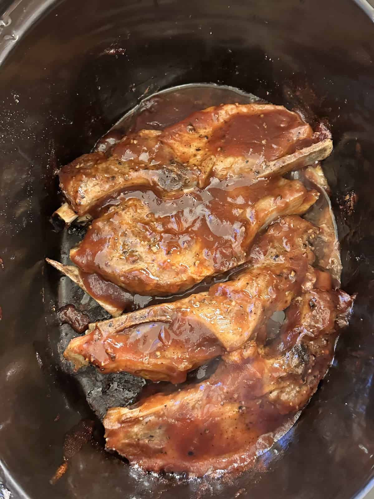 country ribs in a crock pot topped with barbecue sauce