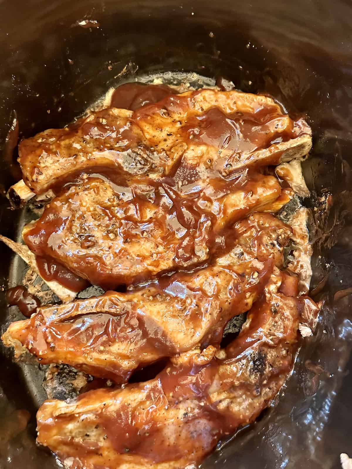 country style ribs in a crock pot with barbecue sauce on top