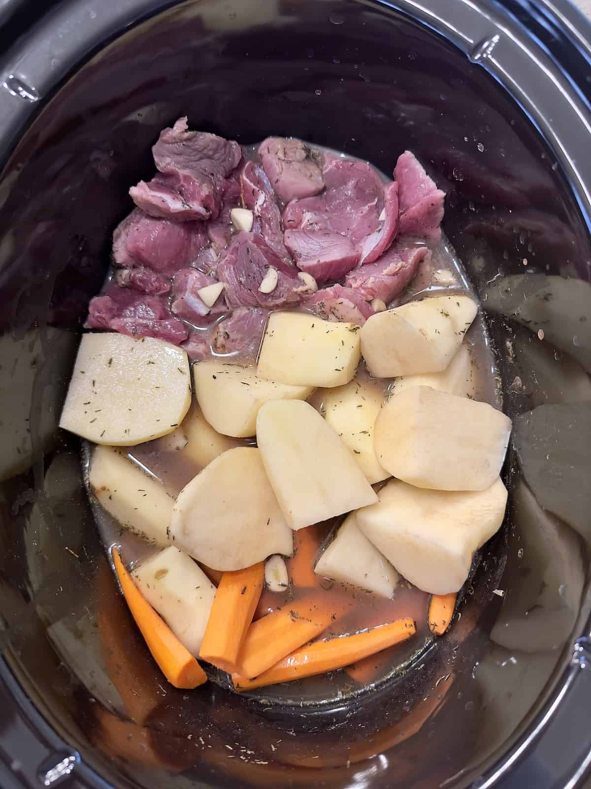 cut leg of lamb, carrots, potatoes, broth and spices in the slow cooker uncooked