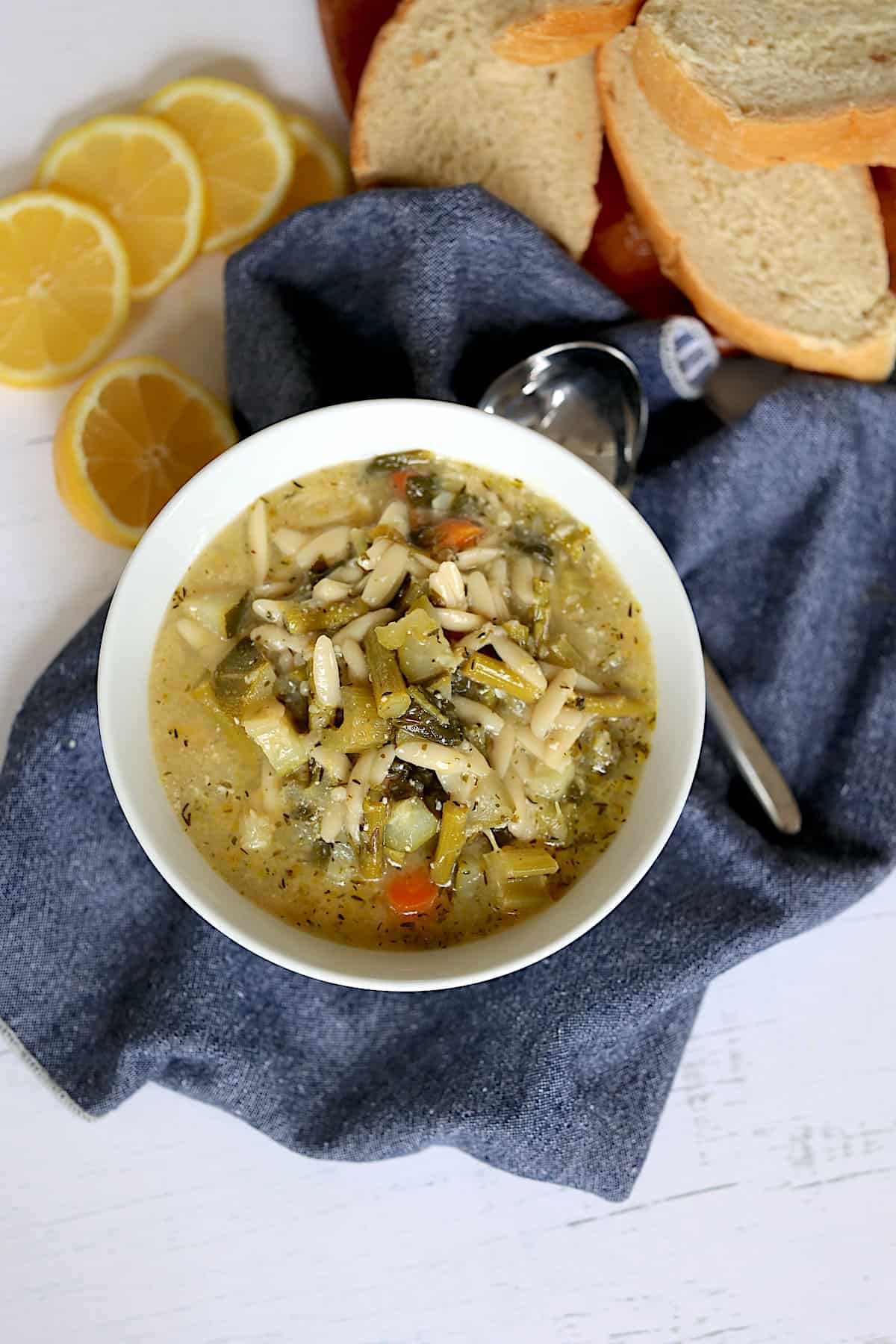 instant pot garden vegetable minestrone soup in a white bowl with bread and lemons