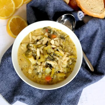 instant pot spring minestrone soup in a white bowl with lemons and bread