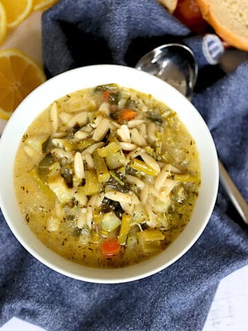 instant pot spring minestrone soup in a white bowl with lemons and bread