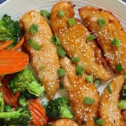 air fryer teriyaki chicken strips on a white plate topped with scallions