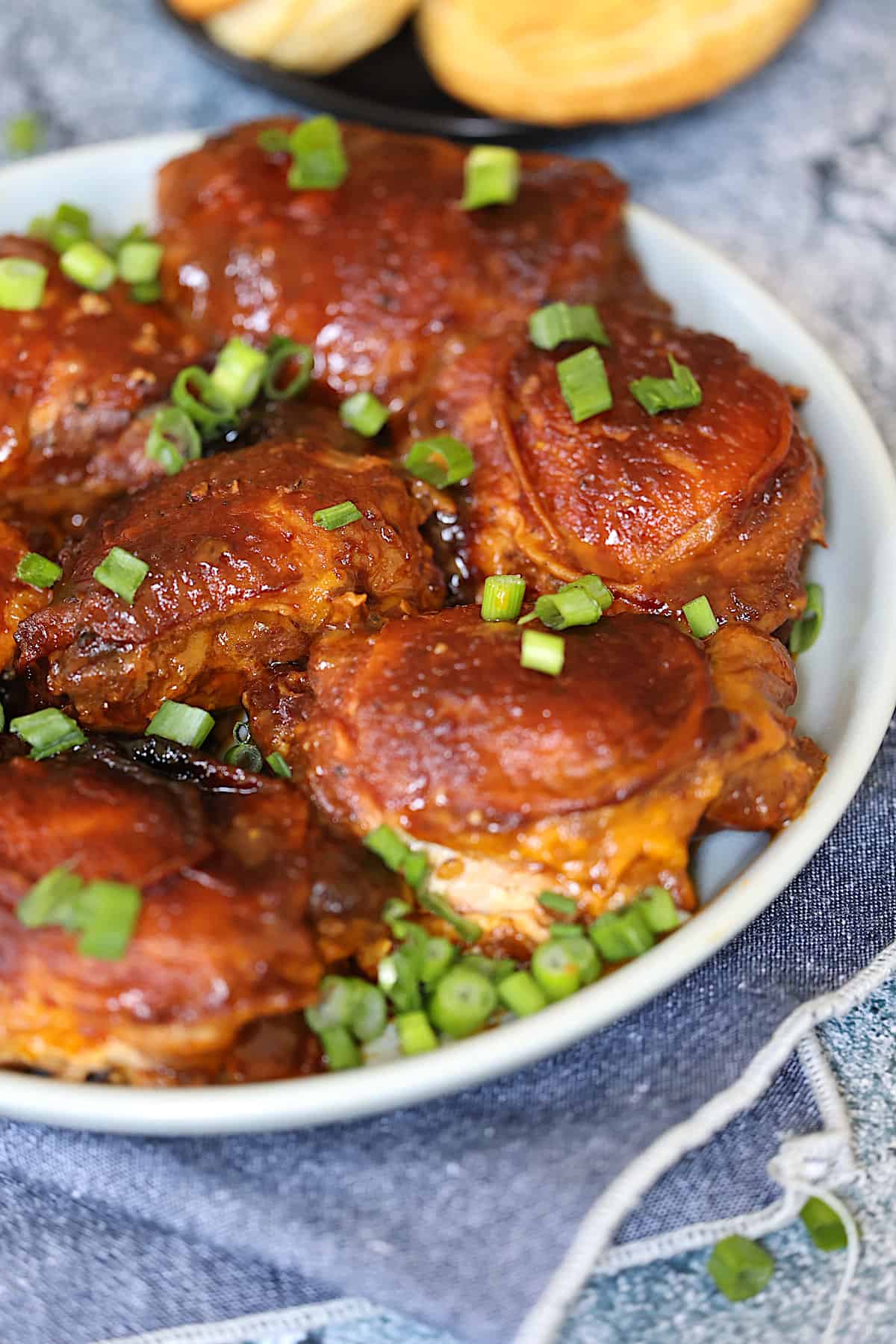 slow cooker bbq chicken thighs with green onions on a gray plate